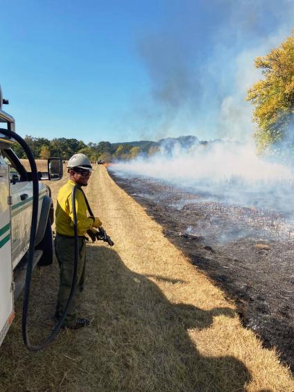 A man standing by the die of the road, wearing FS fire crew gear