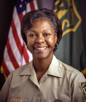Protrait photo of Leslie Weldon. U.S and Forest Service glags in the background
