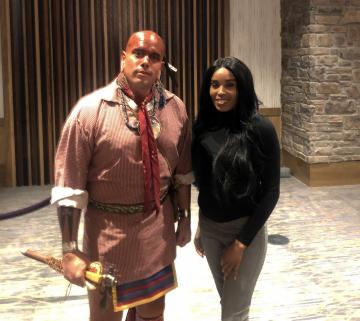 Woman posing next to and American indian dancer