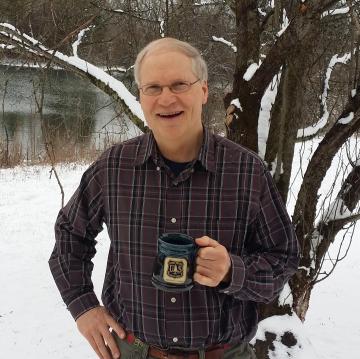 Louis Iverson holding a mug with the Forest Service insignia.