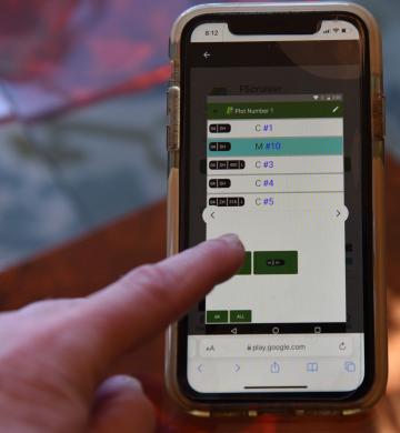 Close-up of timber cruising app on mobile phone. Person's finger taps the screen.