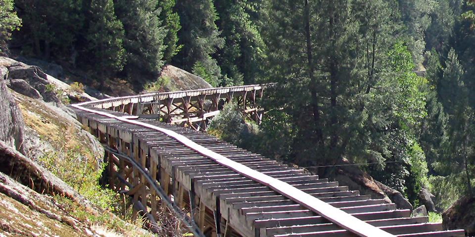 Wooden flume of the Main Tuolumne Canal running down a tree covered gulley.