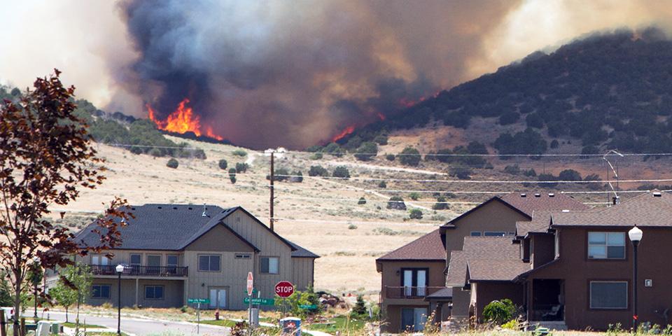A small community of houses with a wildfire raging in the background.