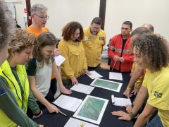 Students gather around a table to review documents.