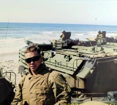 A man in military uniform standing in front of a military vehicle.