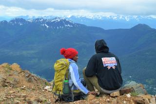 Two people sitting and looking over mountans