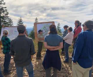 People surrounding a Forest Service ranger on the field.