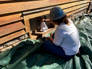 Young woman cleaning window on a restored log home