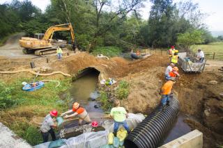 A picture of a culvert construction site showing several workers and large equipment.