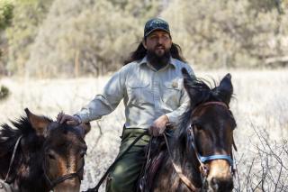 Employee on horseback leads a second horse.