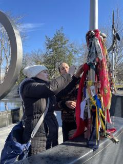 Deputy Chief Jaelith Hall-Rivera and Reed Robinson, director of the Office of Tribal Relations, tie a red cloth around a pole outside the National Museum of the American Indian.