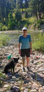 Sara Brown standing with her dog next to a river.