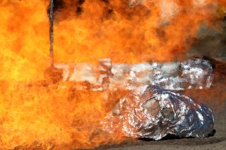 Emergency fire shelters being tested in a fire. The thin outside layer of reflective material has partially burned away in the shelter closest in the image.