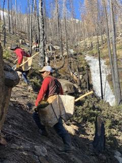 Group of people climbing the side of a mountain with spades and equipment