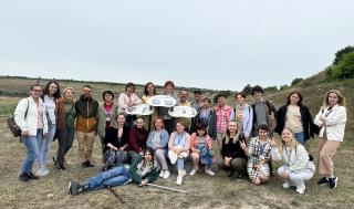 Group photo surrounding interpretive signs at tree-planting site in Moldova.