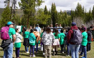 About 20 students and teachers watching a demonstration of the crosscut saw they will use as part of a field station set up to teach outdoor skills. 