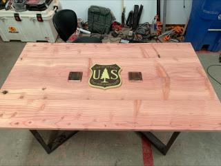 Wood table with FS logo on the middle and electric outlets on each.