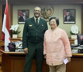 Chief Moore in formal Forest Service uniform poses with Minister Siti Nurbaya in front her office desk.