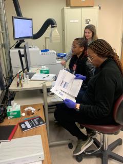Three individuals sitting at a lab station