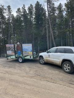 A car parked in front of a sign featuring Smokey Bear