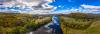 A picture showing slow moving river with grassy forested areas on both sides.