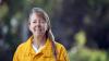 Woman with long hair in yellow fire shirt facing camera for picture