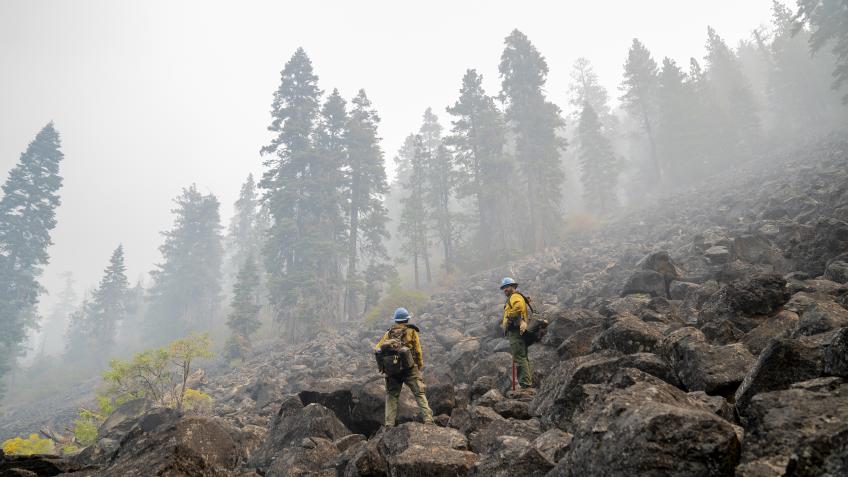 Ryan Johnson and Travis Fuller climb over massive lava rocks as they ascend a mountain.