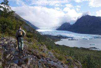 A forest service employee stands on Spencer Bench overlooking Spencer Glacier and the lake as clouds roll in.
