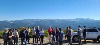 People gather at road overlook with mountain behind