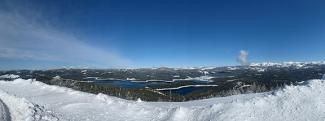 Snowy landscape with large lake and forest behind