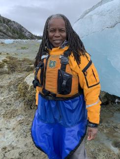 A woman in outdoor work gear stands by an ice flow.