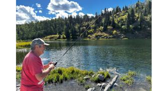 man fishing in lake under blue sky