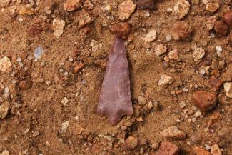 A Native American arrowhead lies in the dirt.