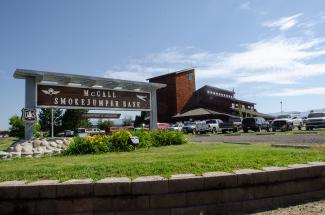 A sign says McCall Smokejumper Base in front of a large, shingled building.