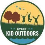 Every Kid Outdoors logo featuring a forest green frame with a grassline splitting the sphere in half. Above the grass is a gold background with blue birds flying above brown trees and the green silhouettes of three children: one jumping in the air, one doing a cartwheel and one standing on ground with arms up in a V shape.