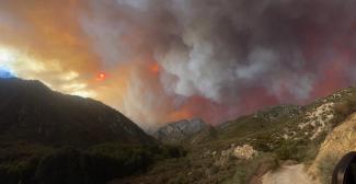 Gray smoke billows over mountainous terraine