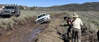 vehicle stuck in muddy road, people, grass, sky