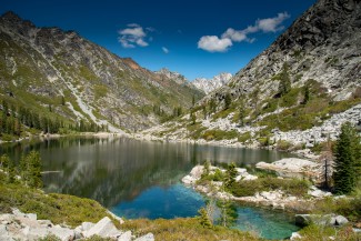 Alpine lake surrounded by step and rocky alpine terrain and forests