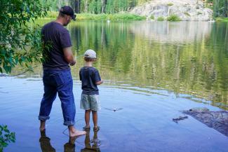 An adult and child fish from the shore.