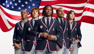 A group of people pose in uniform in front of an American flag.