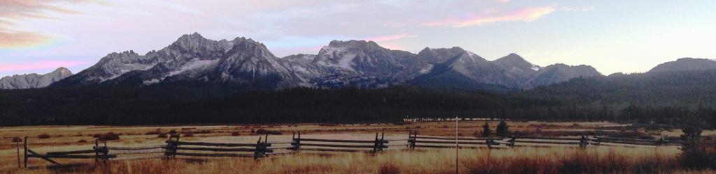 A large mountain range with a log fence in front