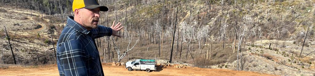 a man points at a construction site on a forest service road