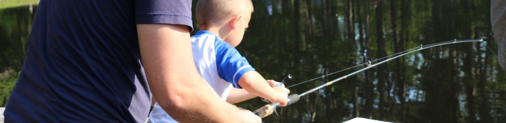 father helping little boy hold fishing pole