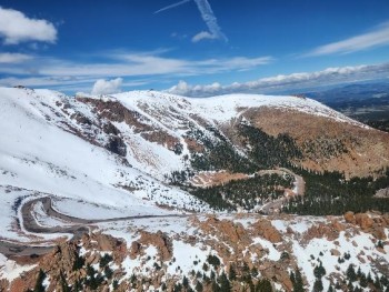 Helicopter view of the highway winding up a snowy mountain.