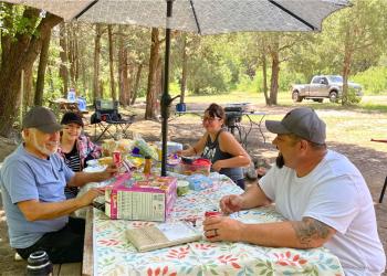 Family sitting down at a picnic table.