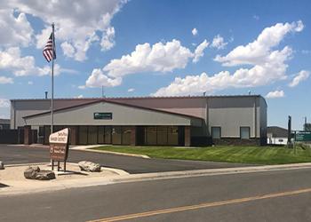 Front of the Santa Rosa Ranger District office that is tan with dark brown trim and room and large front windows.. 