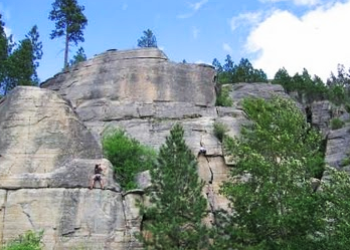 Photo of a large rock wall with some trees in the foreground
