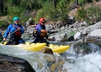 Two people go through rapids on a river in small boats