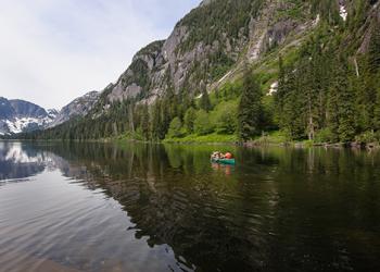 People canoe in a still mountain lake.
