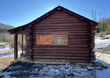 Side of brown log cabin with window.